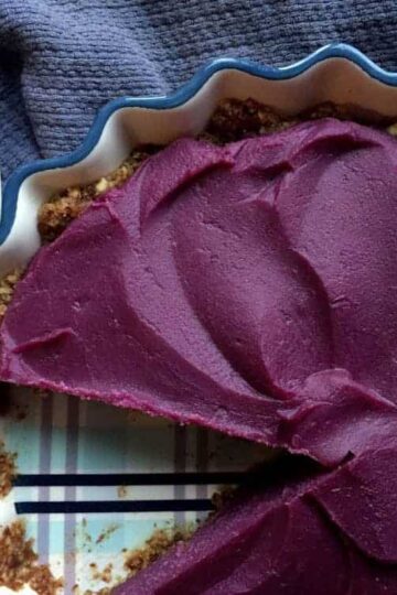 Vegan berry cheesecake with purple berry topping in a tart pan.