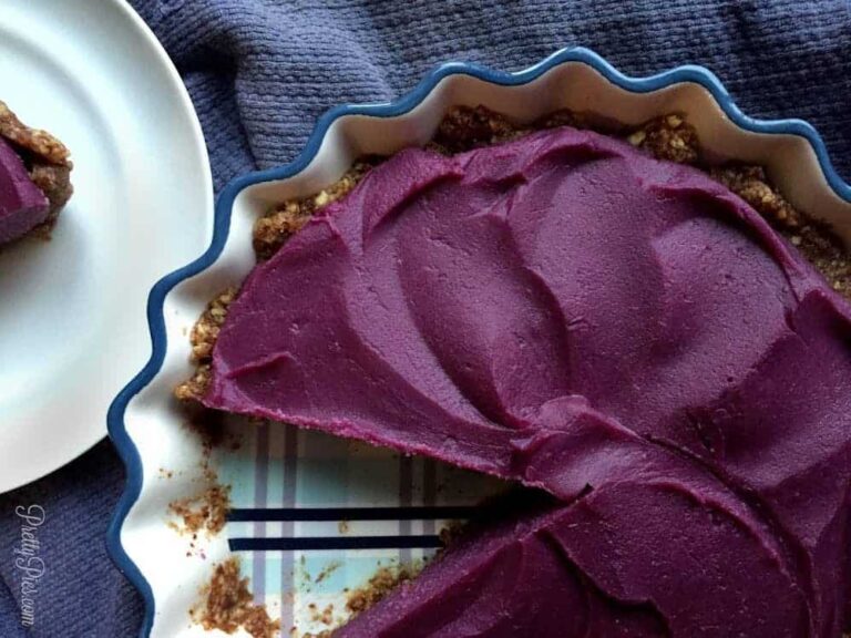 Vegan berry cheesecake with purple berry topping in a tart pan.