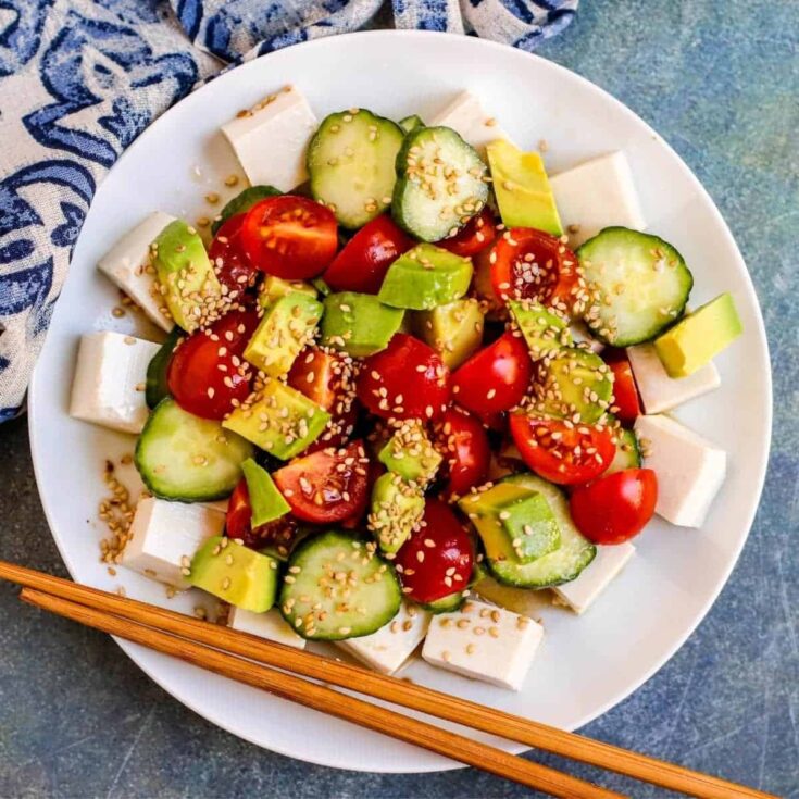 Vegan salad with cherry tomatoes, cucumber, avocado, and tofu for healthy eating.