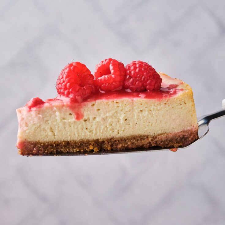 Vegan raspberry cheesecake slice on a silver spatula.