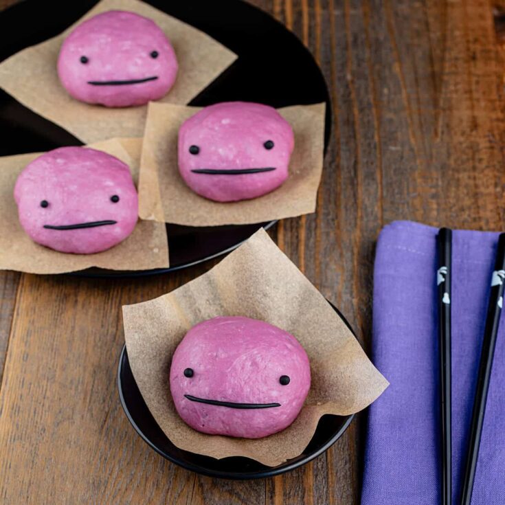 Vegan pink mochi cookies with cute faces on black plates.