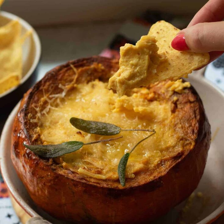 Delicious roasted pumpkin soup served in a pumpkin bowl with sage leaves.