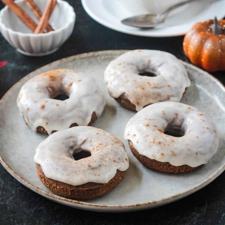 Vegan chocolate donuts with white icing on a rustic plate.