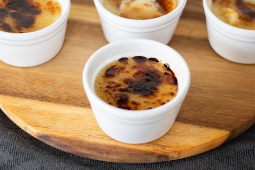 Delicious vegan crème brûlée served in small white ramekins with caramelized sugar topping.
