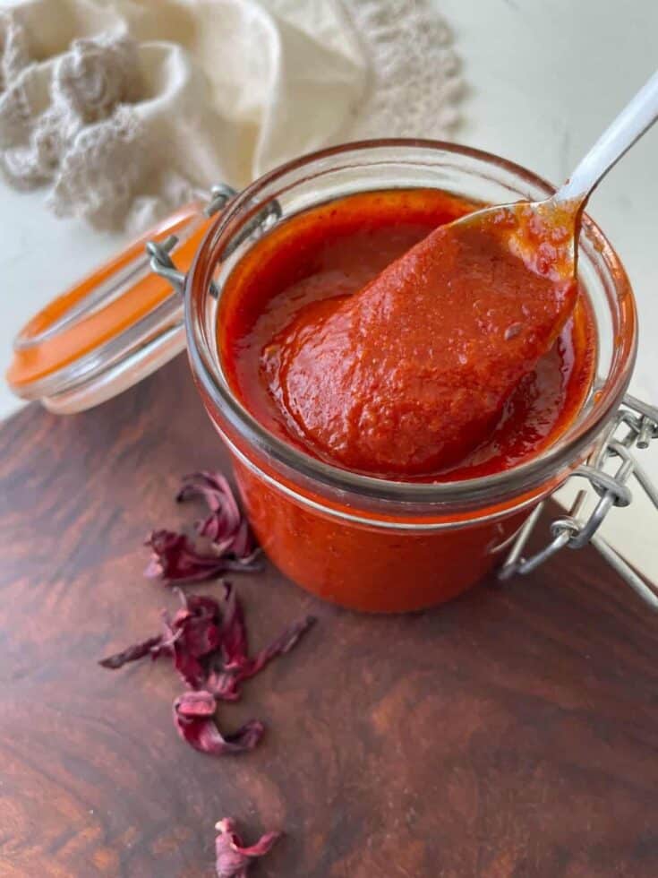 Vegan tomato sauce in a glass jar with a spoon, perfect for pasta or pizza.