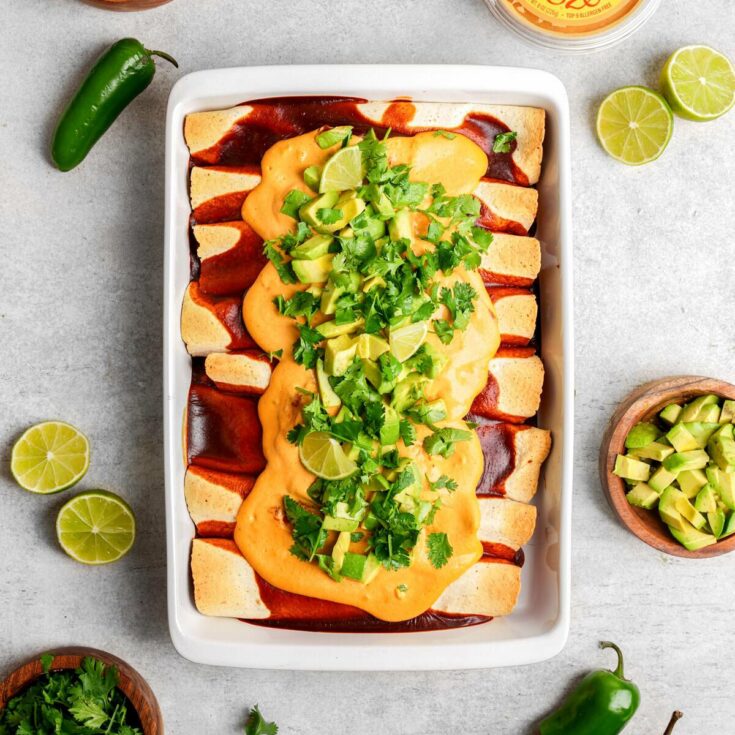 Vegan nachos topped with mango salsa, cilantro, and spicy sauce on a white baking dish. Perfect for.