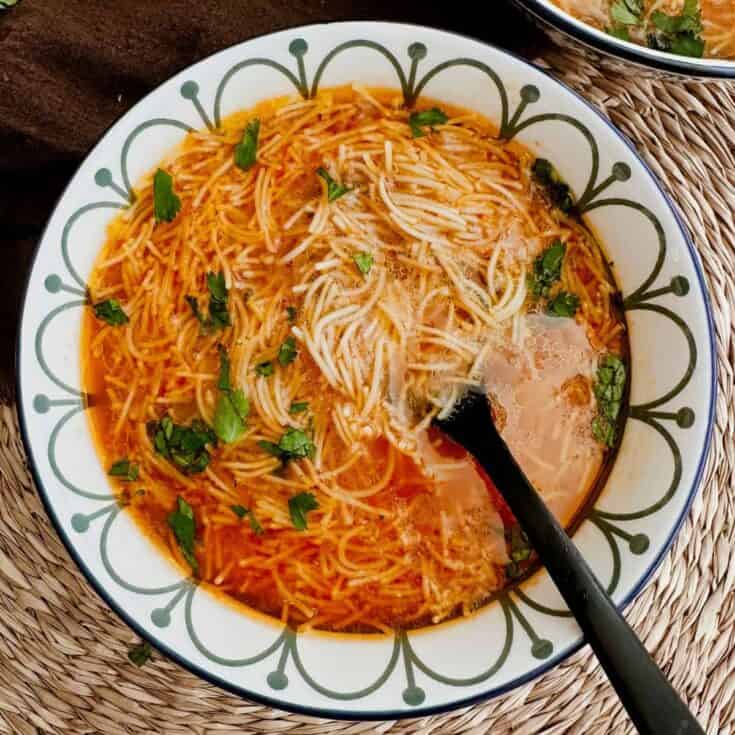 Delicious vegan spaghetti soup with herbs and vegetables in a bowl.
